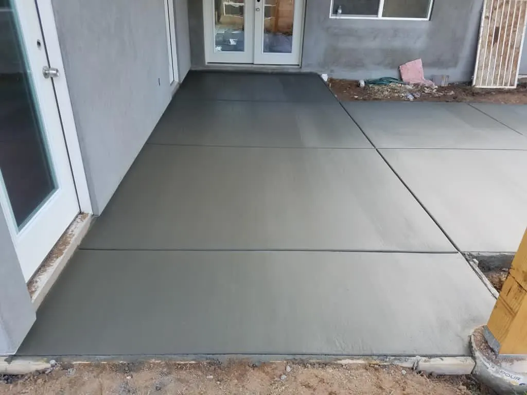 Finished concrete patio slab at the back door of a home with French doors