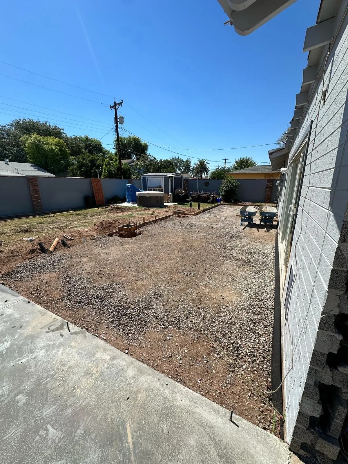 Gravel base compacted next to an existing concrete slab ahead of a replacement pour