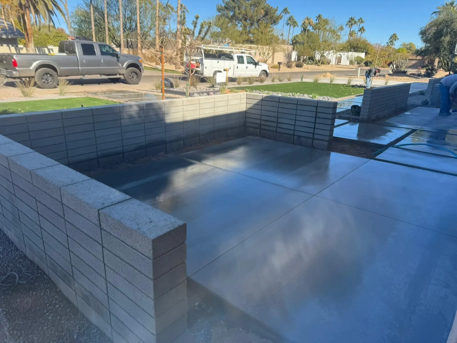 Block retaining wall and finished concrete slab forming a level pad at a residential property