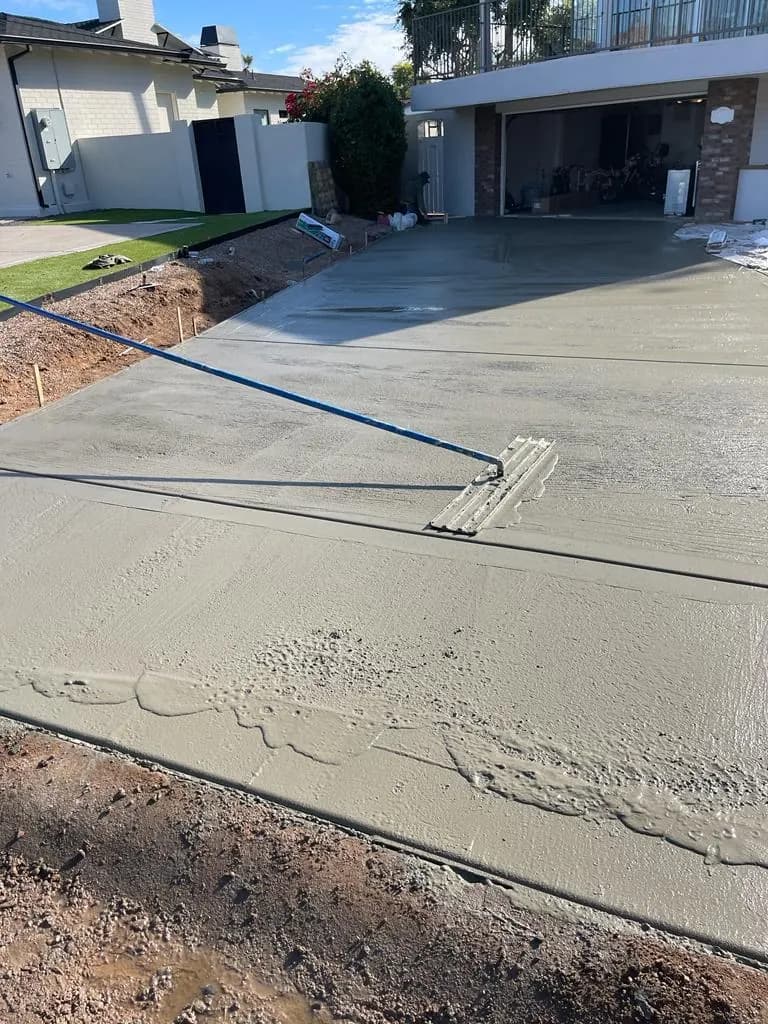 Freshly poured concrete driveway being bull floated in front of a residential garage