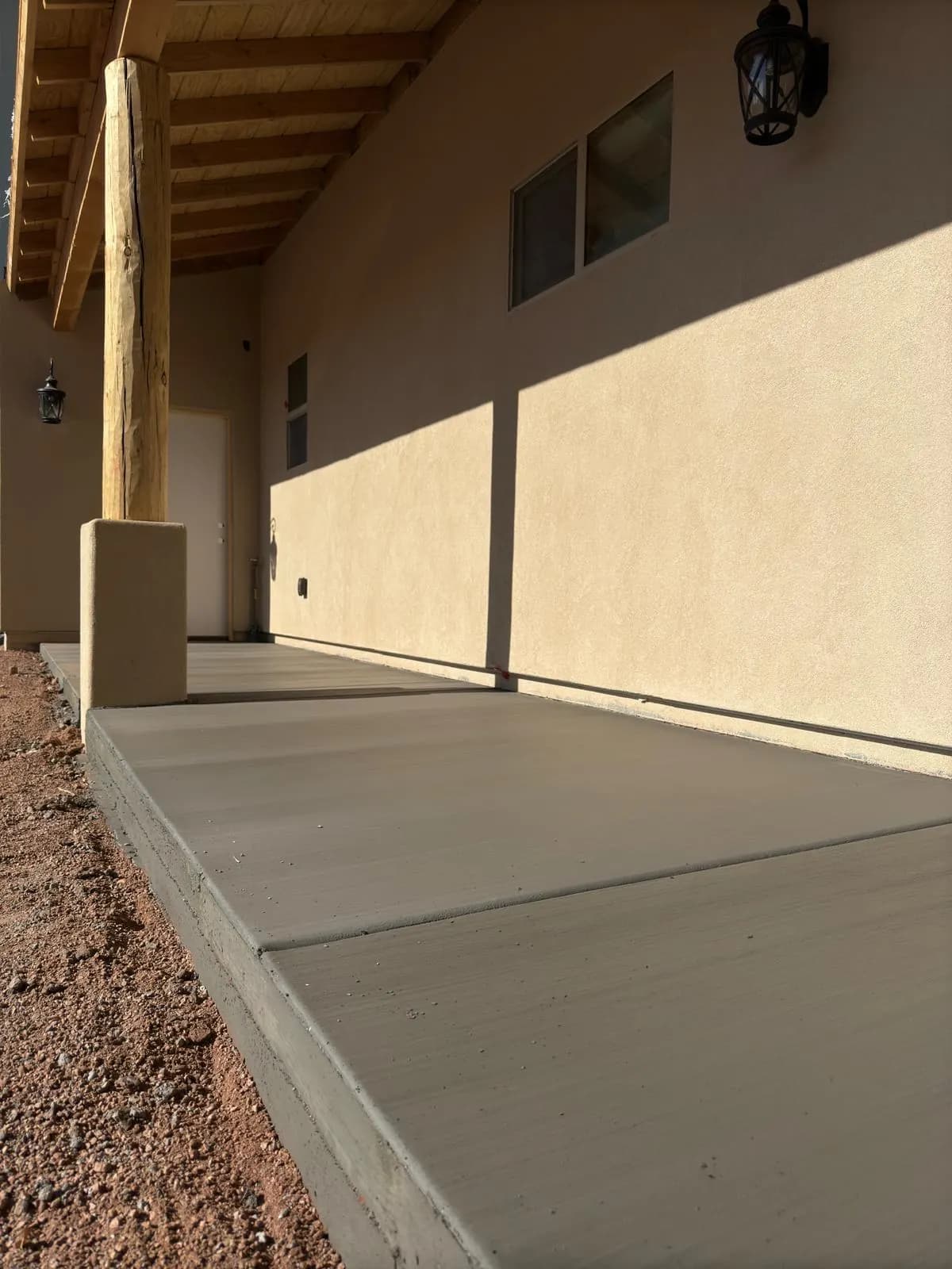 Finished concrete walkway leading under the covered entry of a stucco home