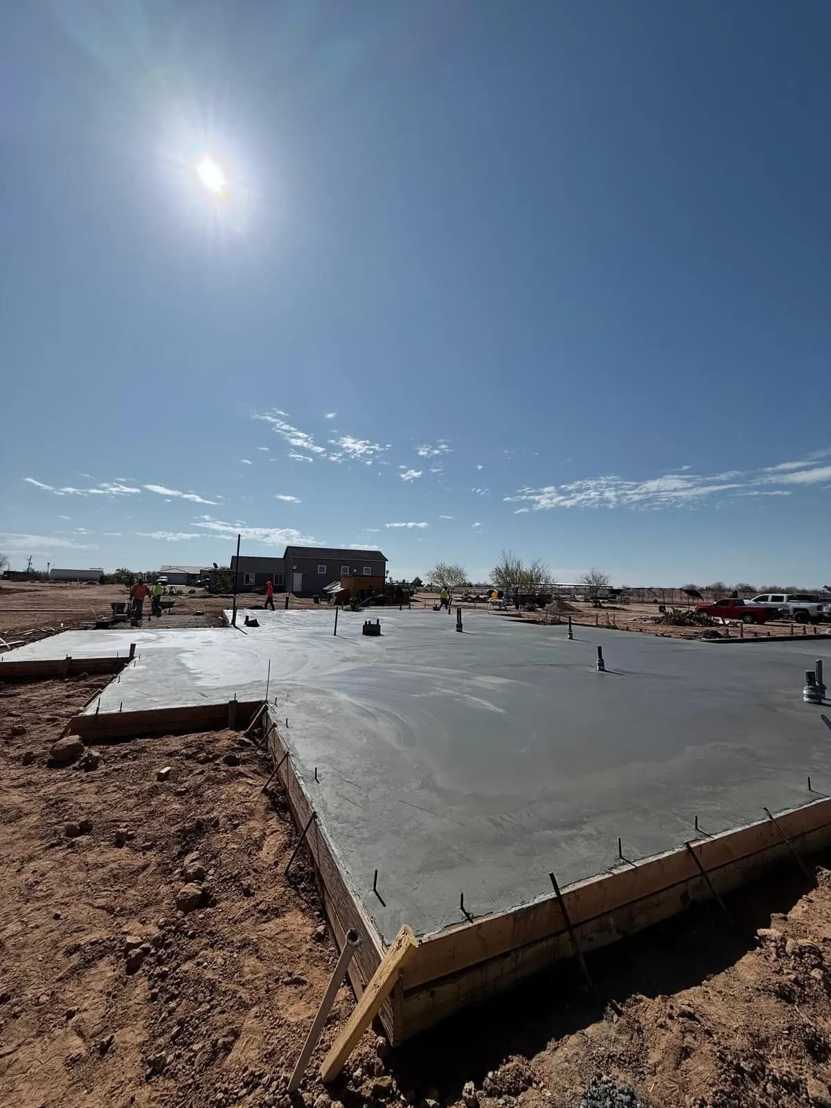 Large fresh concrete foundation slab poured on an open desert lot under a clear sky