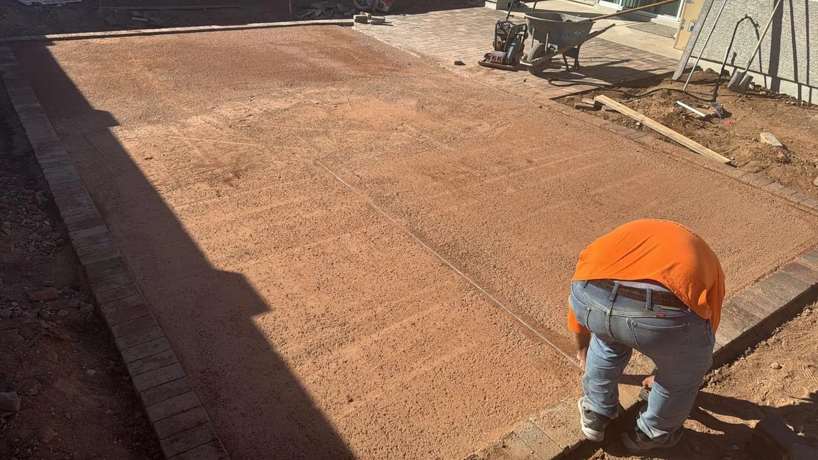 Compacted and graded base prepared for a concrete pour, with a crew member finishing the grade