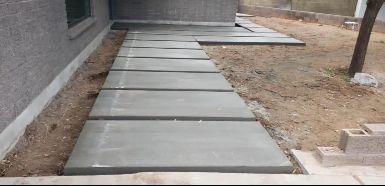 Finished concrete walkway with evenly spaced control joints running alongside a house