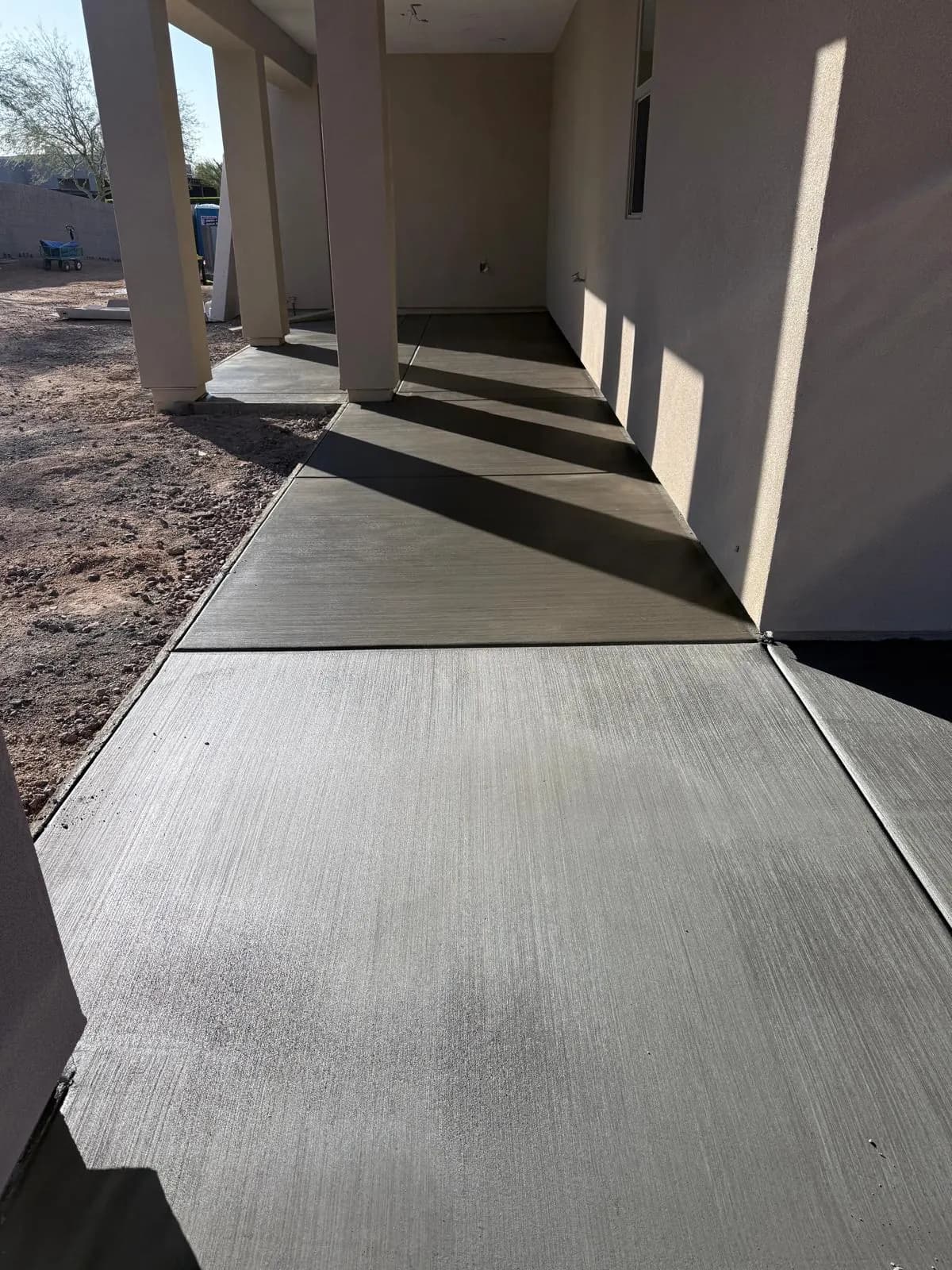 Broom-finished concrete walkway running under the covered walkway of a building under construction
