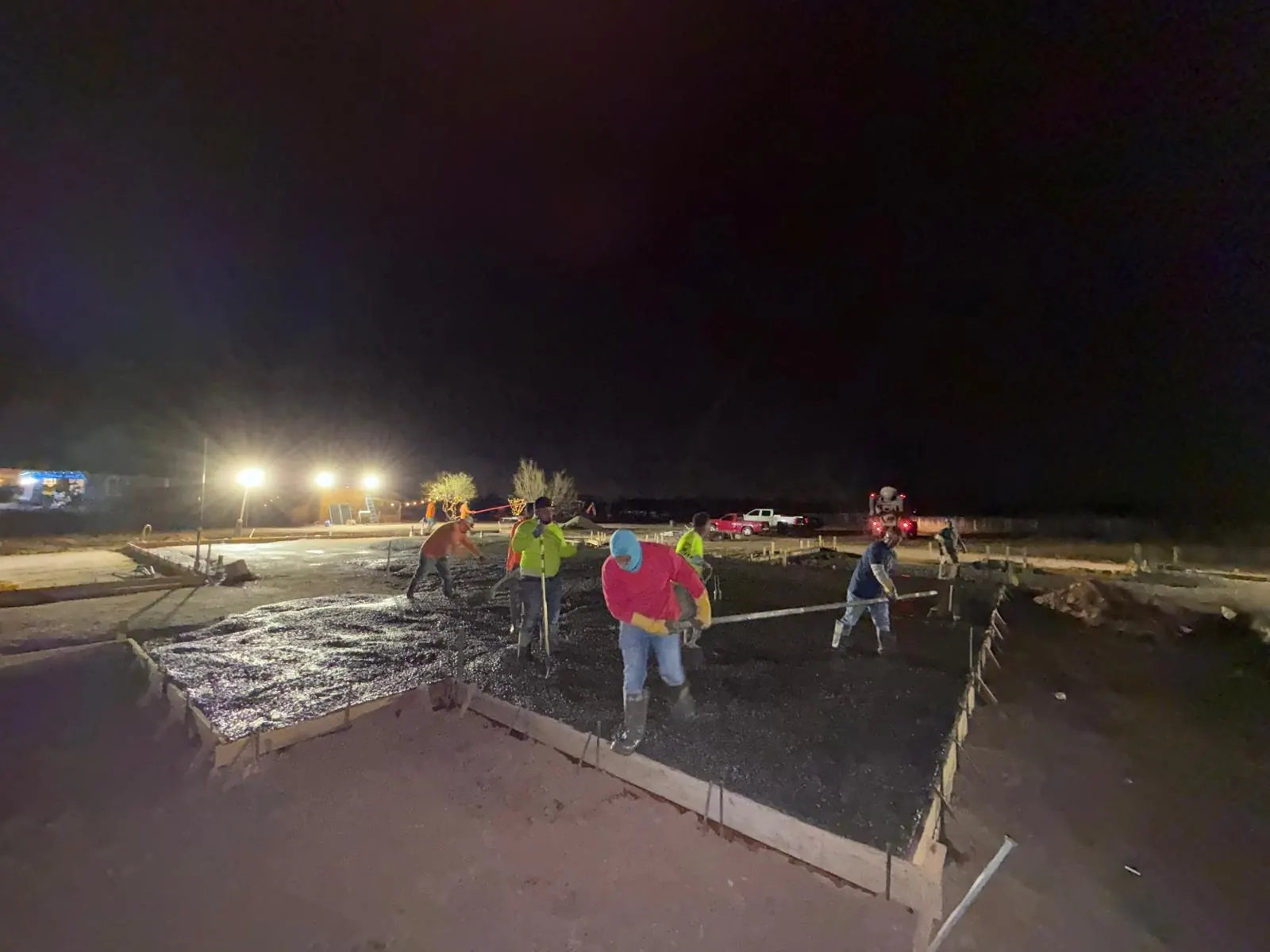 Crew working under portable lights during a night concrete foundation pour