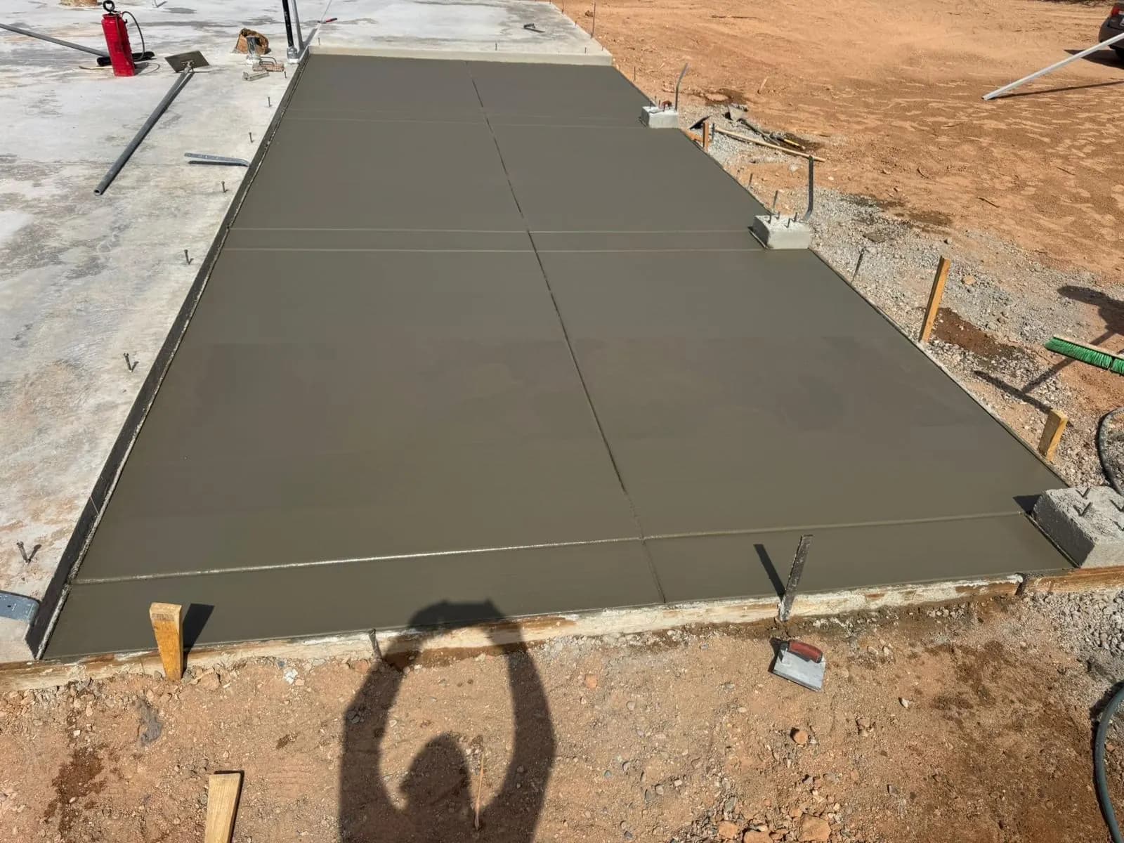 Freshly poured concrete slab in wood forms joining an existing concrete surface